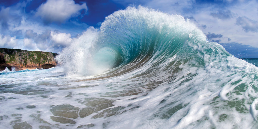 Breaking turquoise wave against a granite Cornish headland